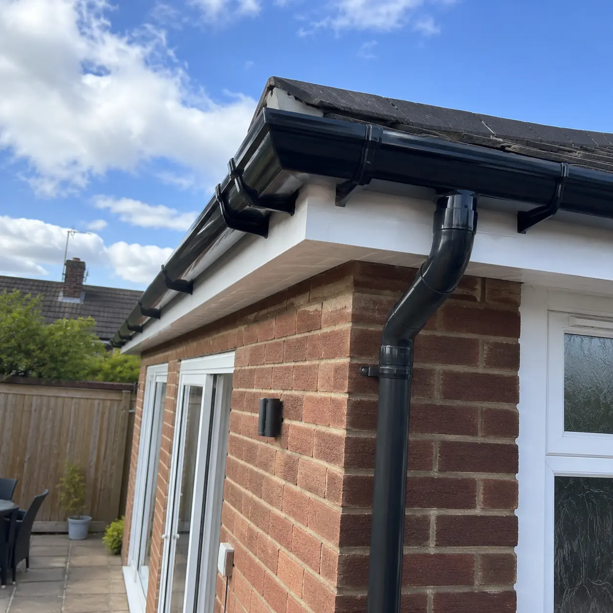New black uPVC guttering and downpipe fitted to a brick house